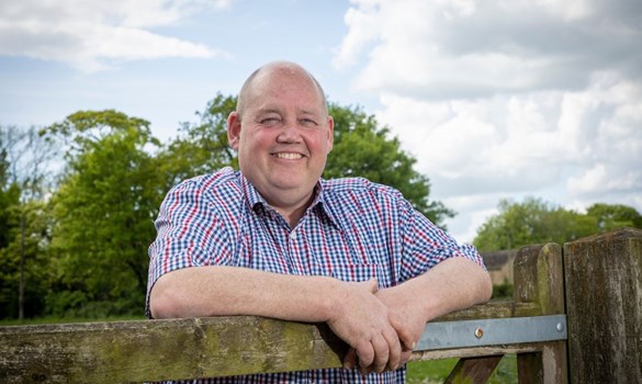 David Jones Cereals farmer smiling on farm fence.